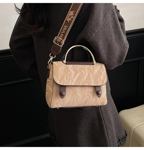 Detail of khaki wrinkled texture handbag with metal handle and wide printed strap