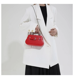 Modèle portant un sac boîte en cuir rouge avec poignée argentée et boucle de ceinture