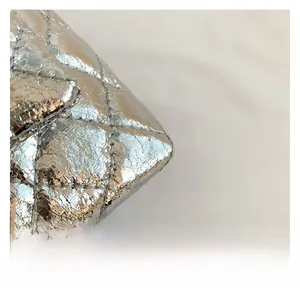 Close-up of silver quilted leather texture and metallic finish on a crossbody bag