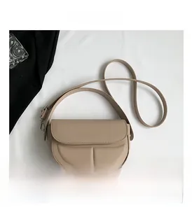 Dettaglio della borsa a sella beige con scritta argentata e tracolla regolabile