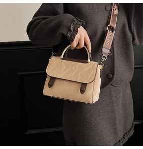 Detail of beige wrinkled texture bag with gold metal handle and printed wide strap