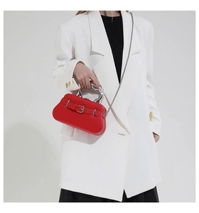 Détail du sac boîte en cuir rouge avec poignée argentée et sangle à boucle de ceinture