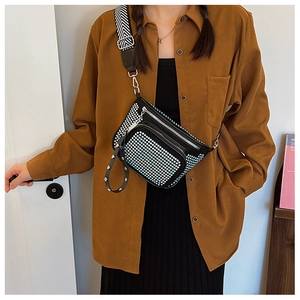 Close-up of black crossbody bag with blue rhinestones and striped strap on model