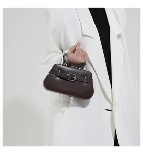Détail du sac en cuir marron foncé avec poignée argentée et boucle de ceinture chic