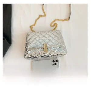 Detailed view of large quilted silver handbag with gold chain strap and metal clasp closure