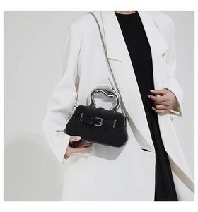 Détail du sac en cuir noir avec poignée en métal liquide et boucle de ceinture argentée