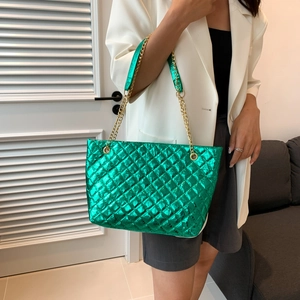 Quilted green metallic tote bag with gold chain strap shown on a white blazer model