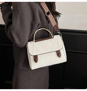 Detail of white vintage crossbody bag featuring pleated texture and wide printed strap