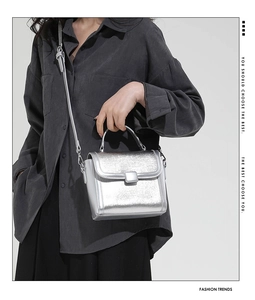 Detail of silver metallic handbag with brushed texture and adjustable shoulder strap