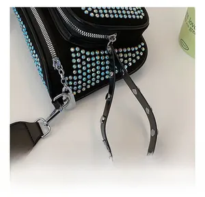 Detail of silver hardware and gradient blue rhinestones on a black crossbody bag