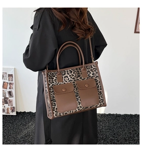 Detail of leopard print tote bag with brown leather handles and flap pockets on a model