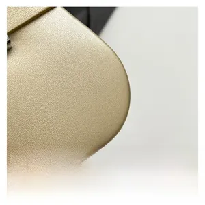 Gros plan du cuir grainé doré champagne avec coutures précises sur le coin du sac