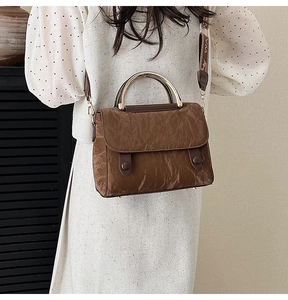 Detail of vintage brown textured handbag with gold metal handle and jacquard strap