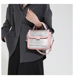 Detail of contrast color pink leather handbag with silver metallic panel and shoulder strap