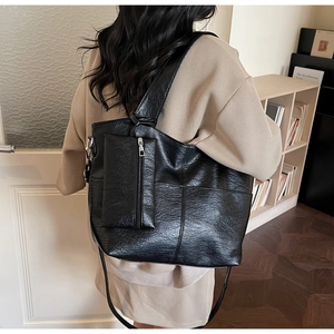 Detail of a black large vintage tote bag with soft leather texture and small pouch