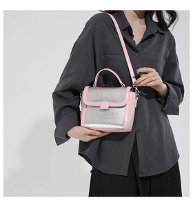Detail of pink and silver color-block crossbody bag shown on a model for size perspective