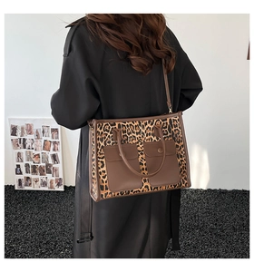 Detail of leopard print tote bag featuring dual front pockets and adjustable leather strap