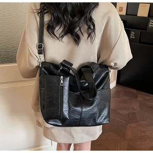 Detail of black pebbled leather tote bag featuring a matching zipper pouch and strap
