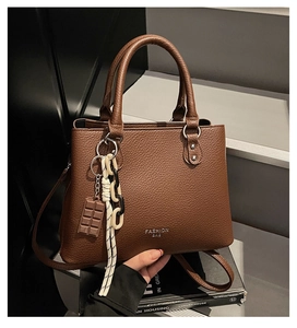 Close-up of litchi pattern leather detail with decorative charms and adjustable strap