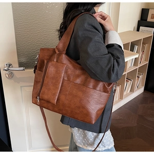 Detailed view of brown leather tote bag showing large capacity and lychee texture