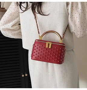Detail of red quilted mini box bag with metallic beads and gold top handle