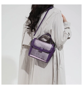 Detail view of a purple textured leather baguette bag worn by a model on shoulder