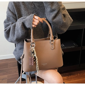 Detail of dark brown lychee grain handbag with FASHION BAG text and chocolate charm