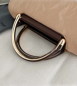Detail of golden circular metal handle and marble texture on light brown handbag