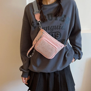 Pink studded crossbody chest bag with wide stripe strap shown on a fashion model