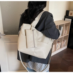 Close-up of cream faux leather tote bag with stitching detail and mini pouch on model