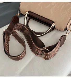 Detail of beige textured leather handbag with brown handles and jacquard strap