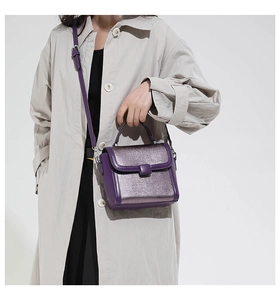 Close-up of stylish purple handbag with glitter panel shown with a beige trench coat