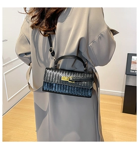Détail de la texture en cuir tressé et du fermoir doré sur le sac à main noir avec bandoulière