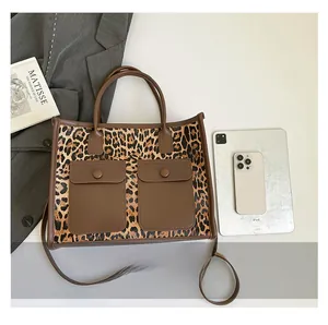 Detail of leopard print tote bag with brown leather pockets, dual handles and shoulder strap