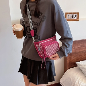 Fuchsia crossbody bag with silver studs and striped strap in a lifestyle setting