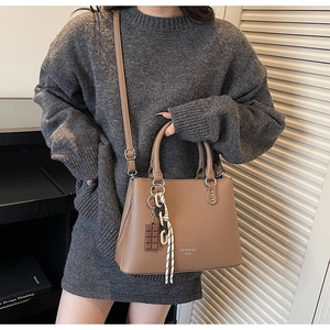 Detail of brown litchi pattern leather handbag with chocolate charm and shoulder strap