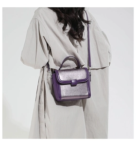 Detail of purple crossbody bag with glitter finish on textured faux leather and strap