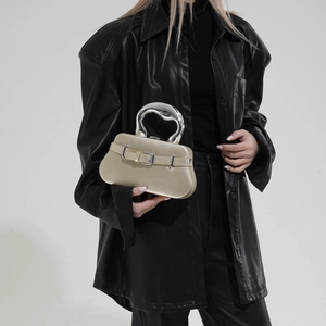 Sac à main boîte doré avec poignée en métal liquide argenté et boucle porté par modèle