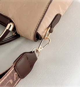 Detail of high-quality golden metal lobster clasp and woven shoulder strap on beige handbag