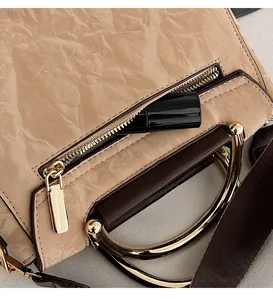 Detail of beige textured handbag featuring a functional back zipper pocket and brown handle