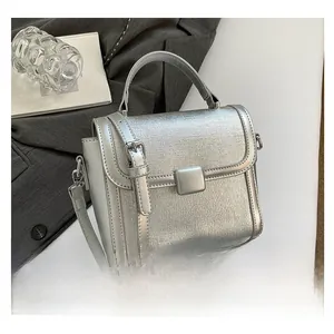 Detailed macro view of the silver crossbody bag's metallic texture and square lock