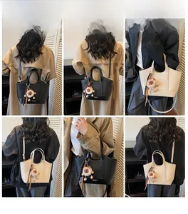 Detail der Litschi-Leder-Eimertasche mit Löwenanhänger und abnehmbarem Gurt