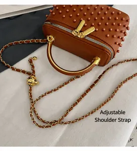 Detail of brown leather box bag with pearl top, golden handle and adjustable chain