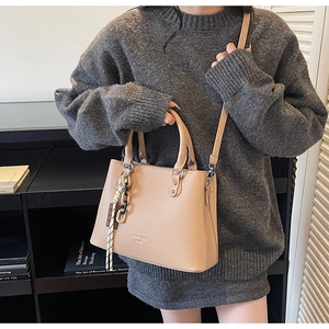 Detail of apricot lychee pattern handbag featuring decorative chain and fashion text