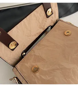 Close-up of golden magnetic buckles on beige pleated leather handbag with premium finish