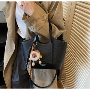 Detail der schwarzen Beuteltasche mit Litschi-Struktur Leder und kleinem Bären-Anhänger