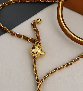 Macro detail of golden ball adjustment buckle on a leather-intertwined chain strap