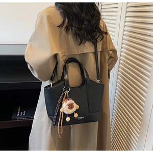 Detailansicht der schwarzen Beuteltasche mit Litschi-Muster und Plüsch-Lamm-Anhänger
