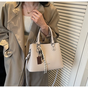 Detail of cream lychee pattern handbag with fashion bag text and chocolate pendant accessory