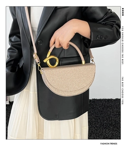Detail of champagne gold sequin saddle bag featuring a unique spiral metal handle